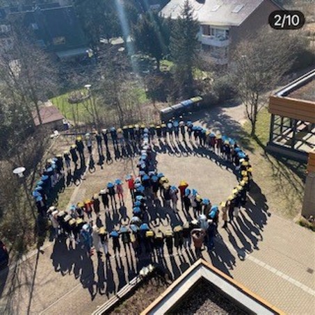Studierende für den Frieden aus der Vogelperspektive aufgestellt zum Friedenszeichen