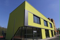 Seitenansicht des moden gestalteten Neubaus des Berufskolleg Düsseldorf. Das Gebäude hat eine mintgrüne Farbe